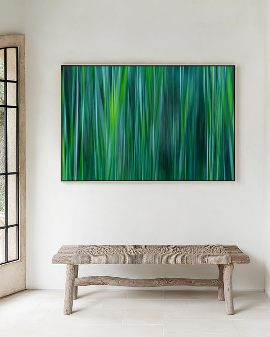 Room with wicker bench with a framed abstract print using shades of green, jade, teal and gray. Cattail leaves.