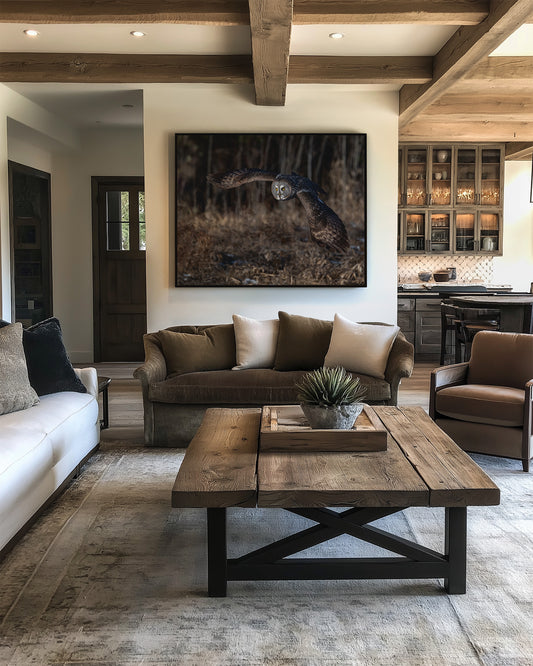 Great Gray Owl flying in woods print on wall in modern living room with brown sofa, white rug, and wooden coffee table.