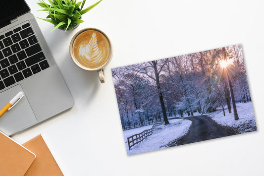 Laptop with a cup of coffee and a snowy landscape print of El Dorado, Arkansas
on a desk.