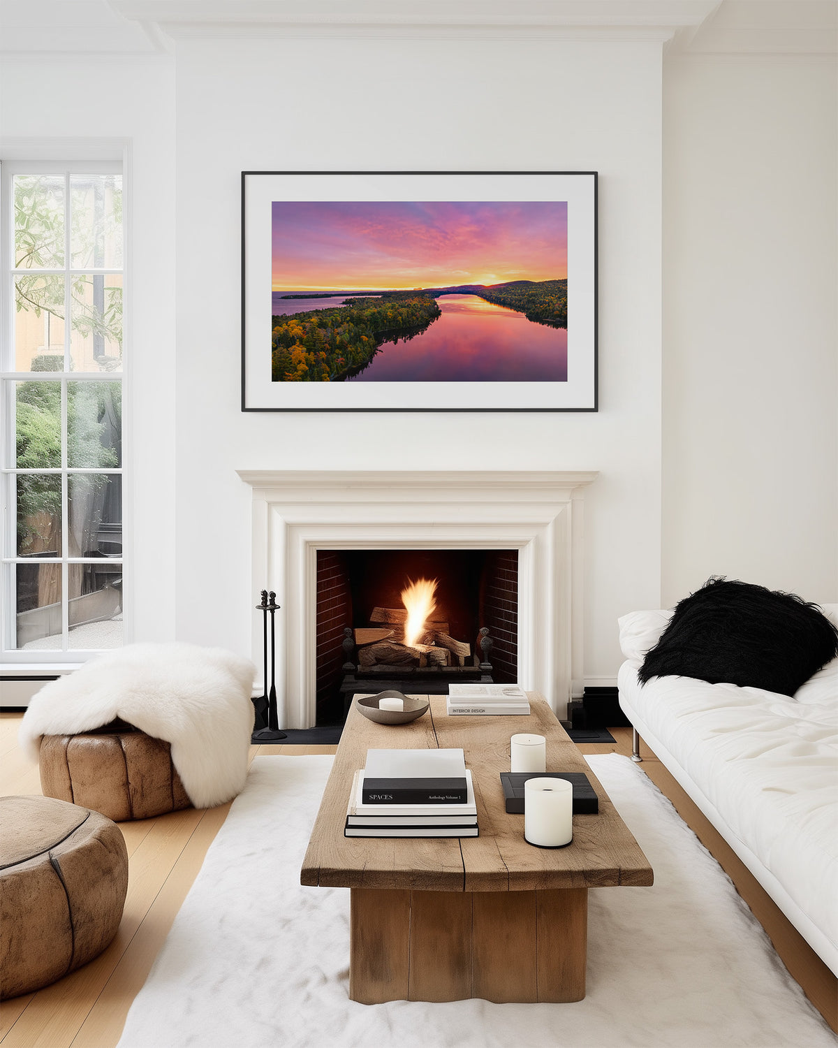 A framed sunrise landscape art print of an Aerial view of Lake Fanny Houe is displayed on a white wall above a fireplace in a modern, stylishly decorated living room.