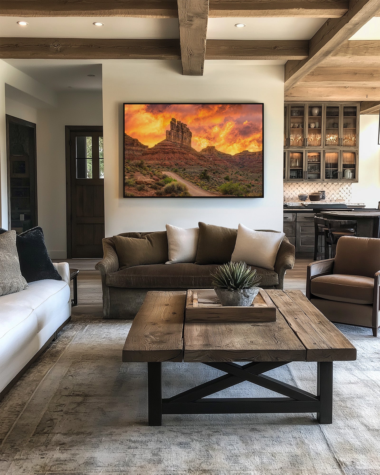 Framed Valley of the Gods iconic formations with an intense sunset in a rustic modern living room with brown sofa, white rug, and wooden coffee table.