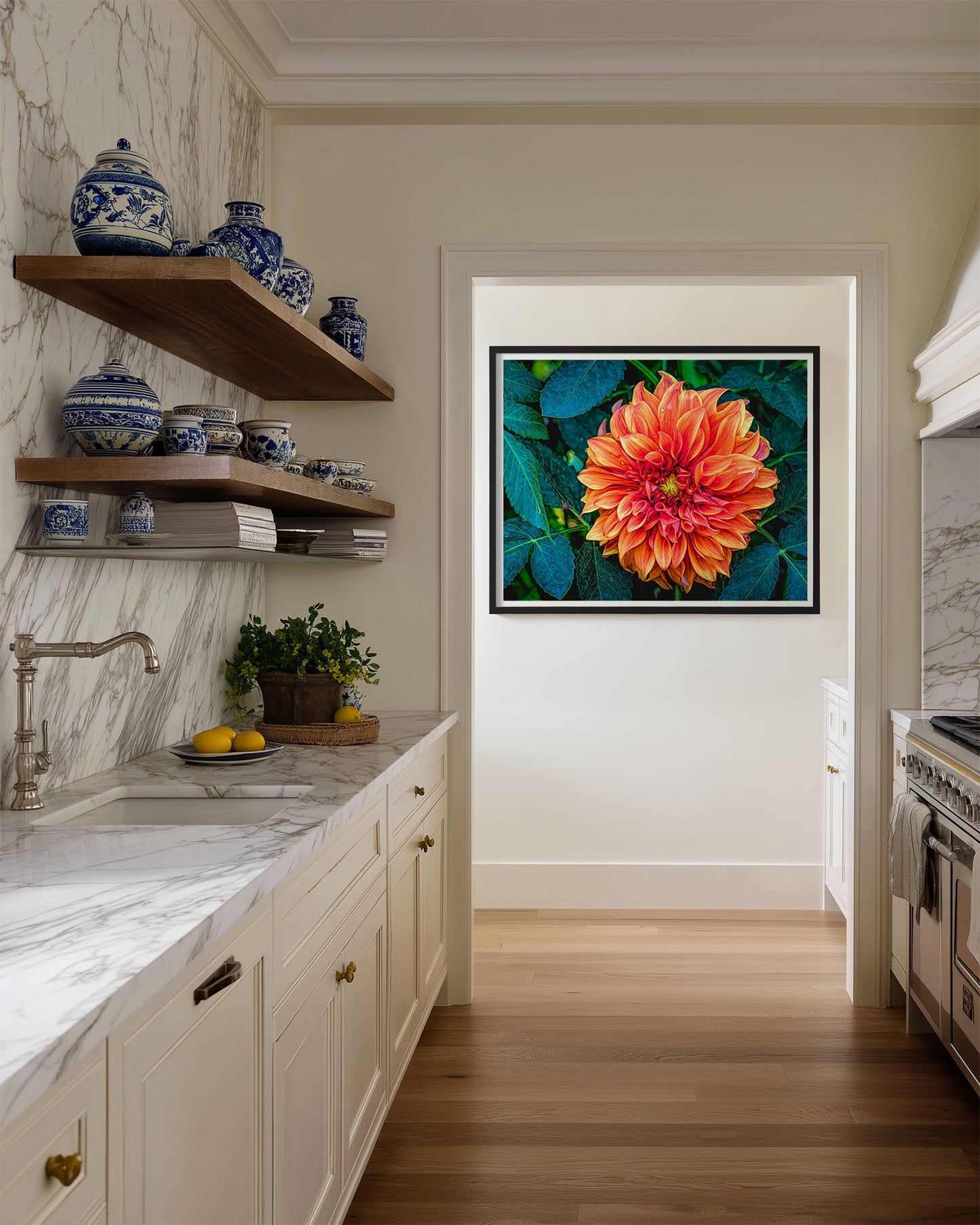 Modern kitchen with marble countertops, wooden shelves, and a framed vibrant orange dahlia flower with green leaves